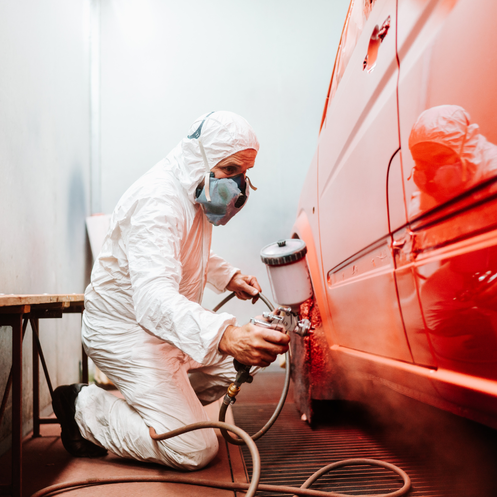 Technician painting orange car